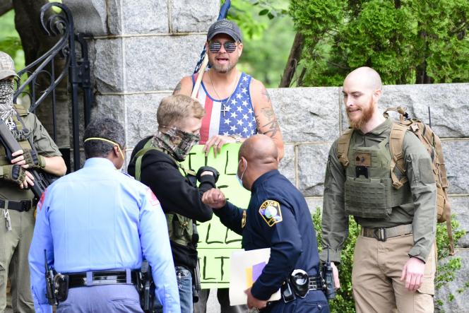 A man in a boogaloo uniform, elbow bumping a law enforcement officer