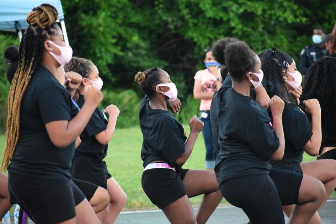 Black girls in Black T shirts and shorts wearing pink masks dancing