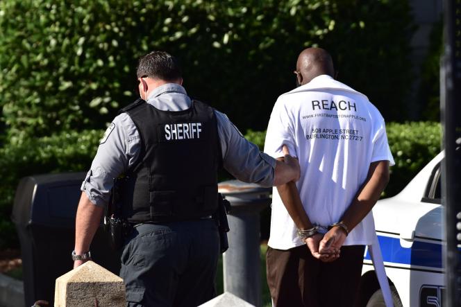 a law enforcement official leading away a handcuffed man