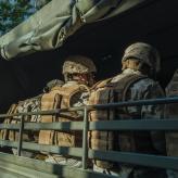 Men in a military uniform, sitting with their backs to us.