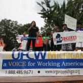 People standing on a platform with a table in front of them with a banner hanging off the table that says "A voice for Working America."