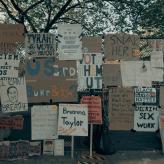 A collection of signs reading slogans for the Black Lives Matter movement covering a fence. 