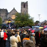 A group of people standing in front of a synagogue with umbrellas open