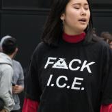 A woman with her eyes closed wearing a black shirt that says "F ck ICE"