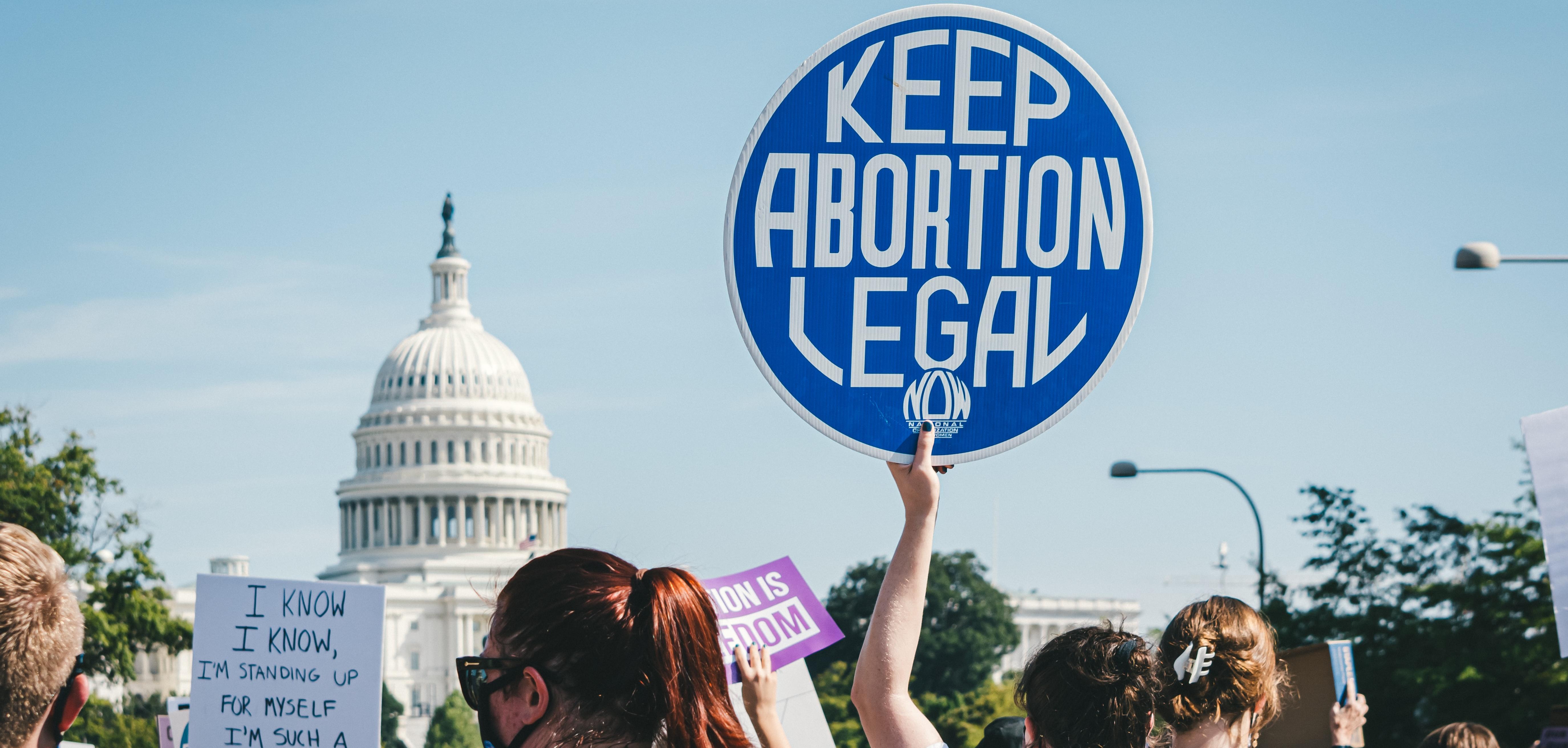 A protester in front of the Capitol holding a sign that says "Keep Abortion Legal"