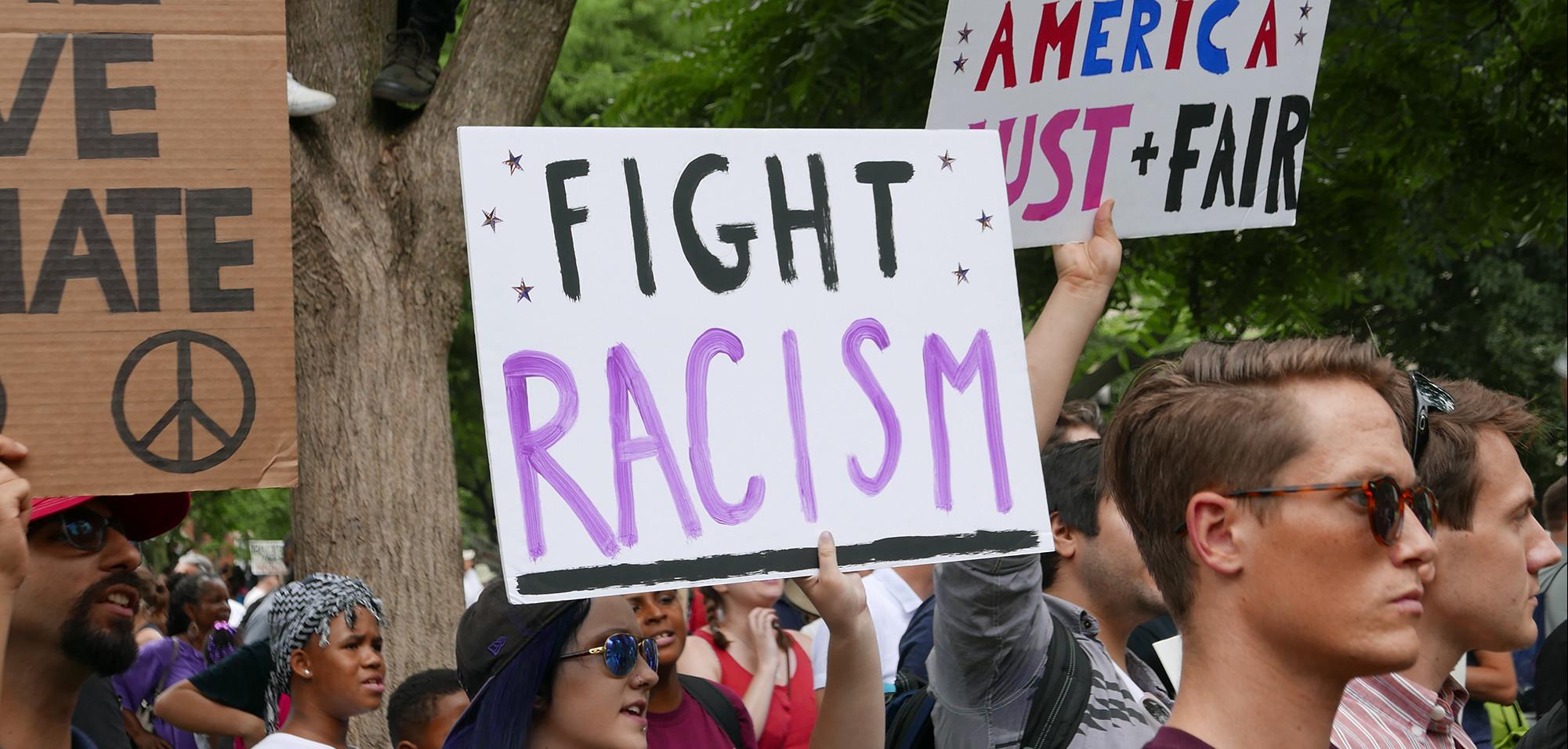 A person holding a sign saying "Fight Racism"