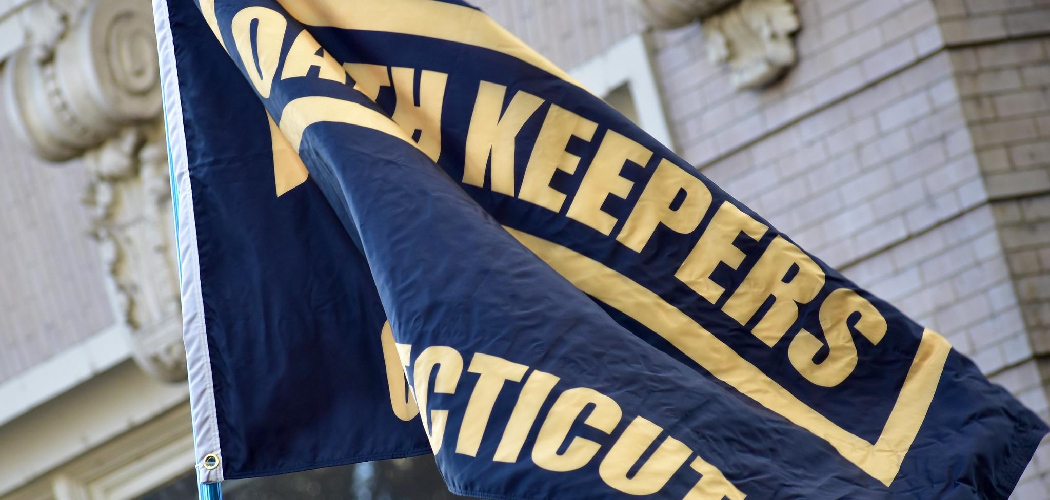 A black flag with the Oath Keepers logo in yellow printed on it.