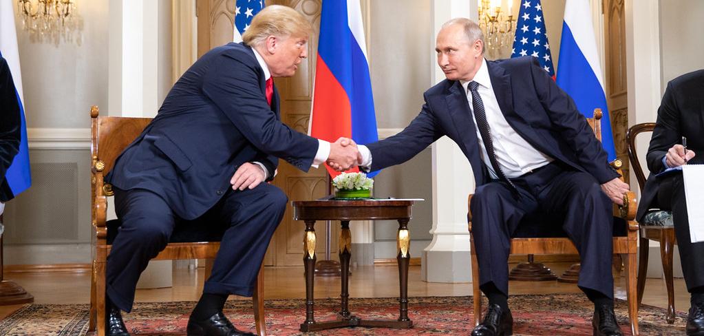 Two men in suits leaning over a table shaking hands