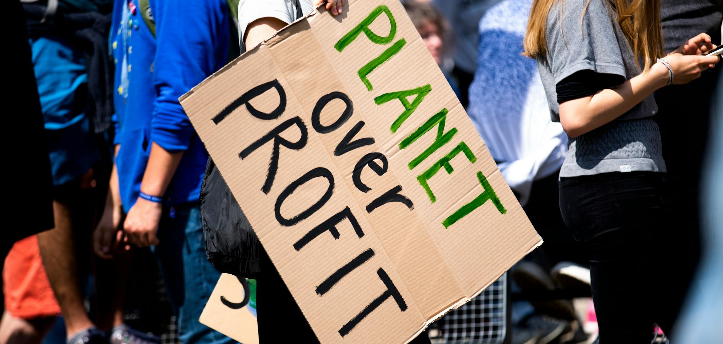 A sign at a protest saying "planet over profit"