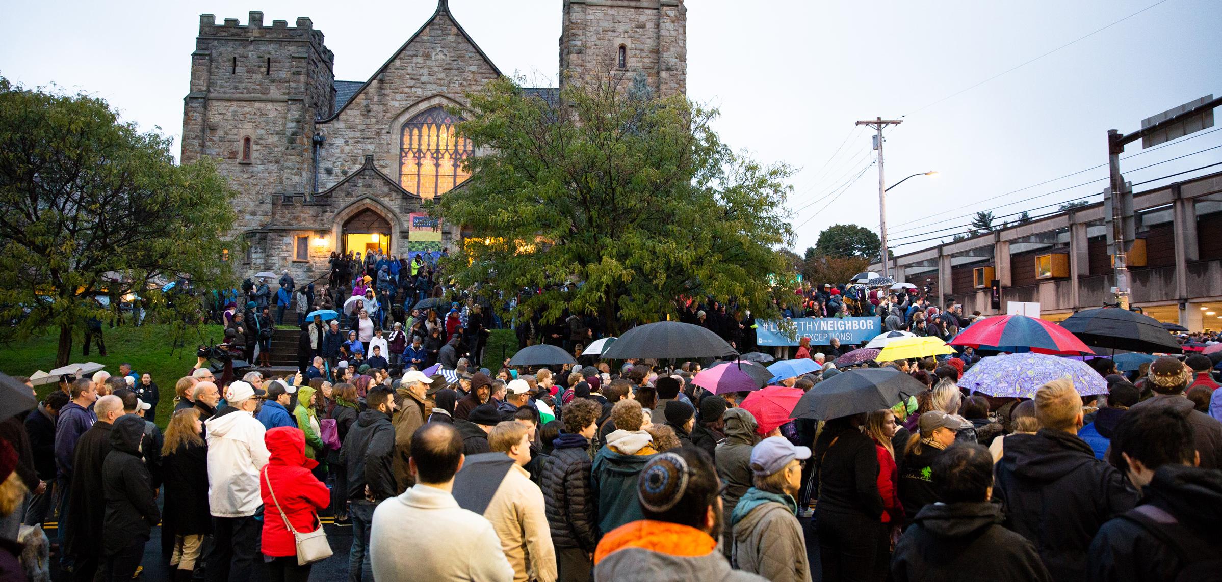 A group of people standing in front of a synagogue with umbrellas open